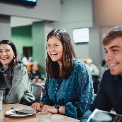 Three Toccoa Falls College students smile in a cafeteria