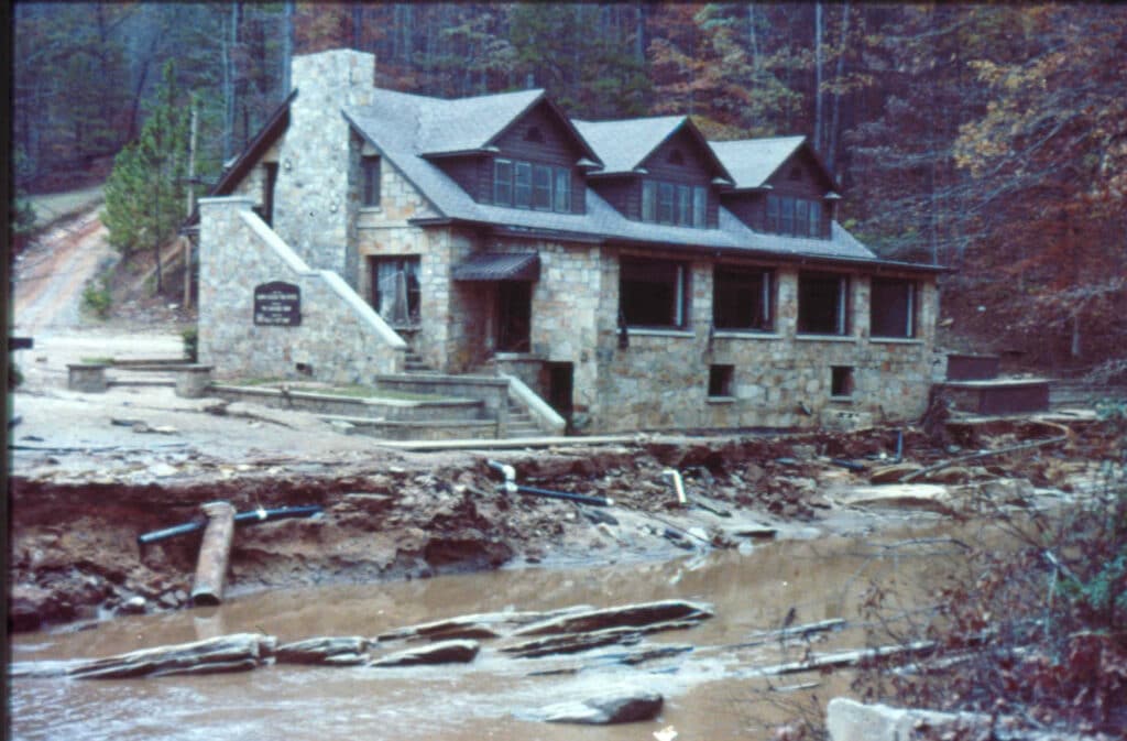 A stone house sits on the bank, near a stream