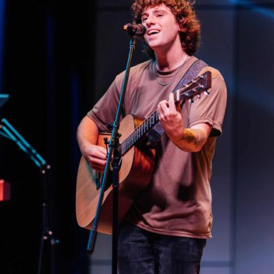 A young man leading worship with a guitar.